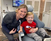 Dental team member smiling next to a young boy in the dental chair