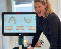Doctor Snow smiling next to a monitor showing digital models of teeth