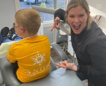 Doctor Snow pointing to the back of a child's T shirt with the Snow Family Dental logo