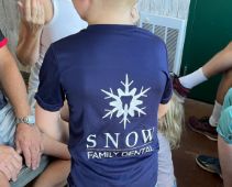 Person wearing a T shirt with the Snow Family Dental logo on the back