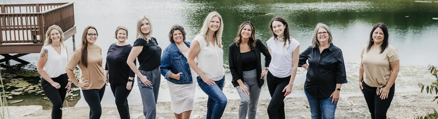 Smiling Frankfort dentist and team members standing on the shore of a small body of water