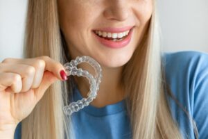 a woman holding retainers in her hands and smiling